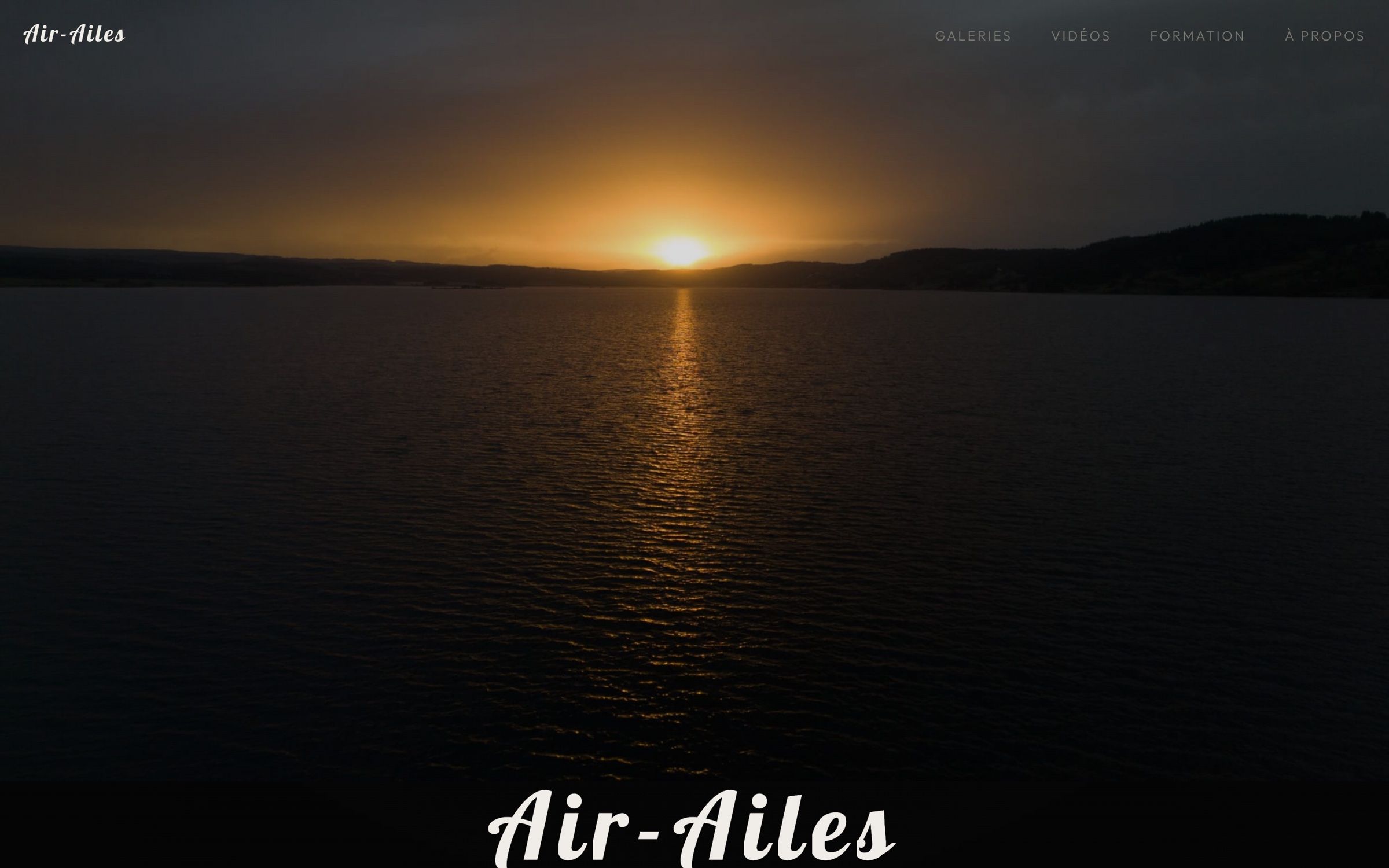 La page d'accueil du site Air-Ailes : un coucher de soleil sur un lac.